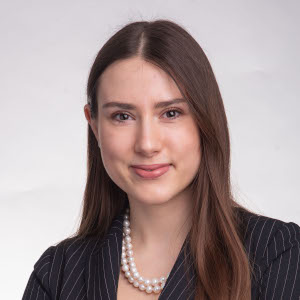 Ritratto professionale di Nina Szadurska, esperta ESG, con blazer a righe sottili e collana di perle